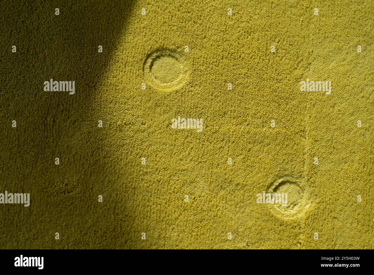 Formes rondes – traînées de tabouret sur tapis jaune, point de vue abstrait Banque D'Images