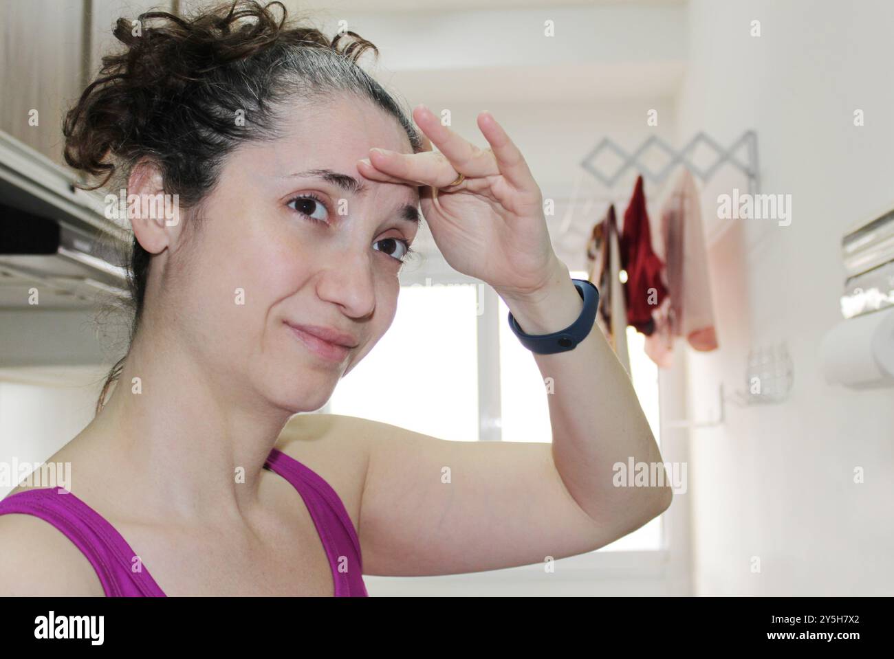 Femme au foyer brune brésilienne cherchant inquiet dans une buanderie minuscule appartement. Femme blanche expressive faisant des travaux ménagers. Femme de femme de ménage de peau blanche. Banque D'Images