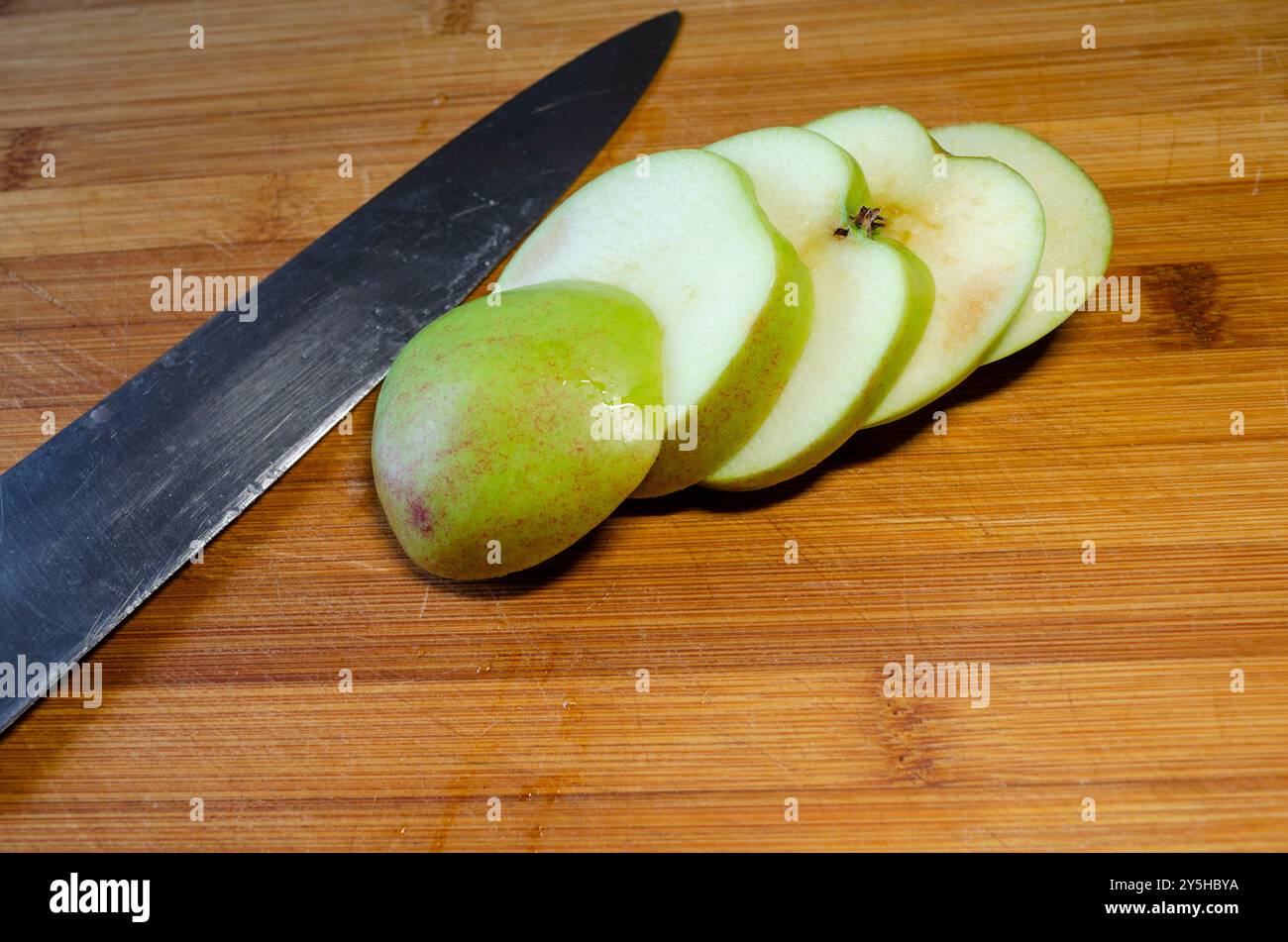 Pommes coupées sur une planche à découper en bois avec un couteau de cuisine Banque D'Images