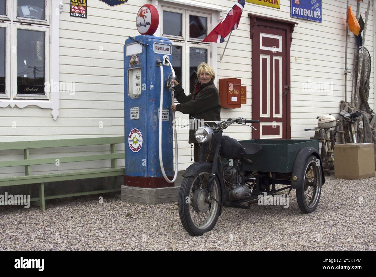 Femme blonde remplissant l'essence pour sa moto dans une ancienne station-service, Kongsfjord, Varanger, Norvège, Europe Banque D'Images