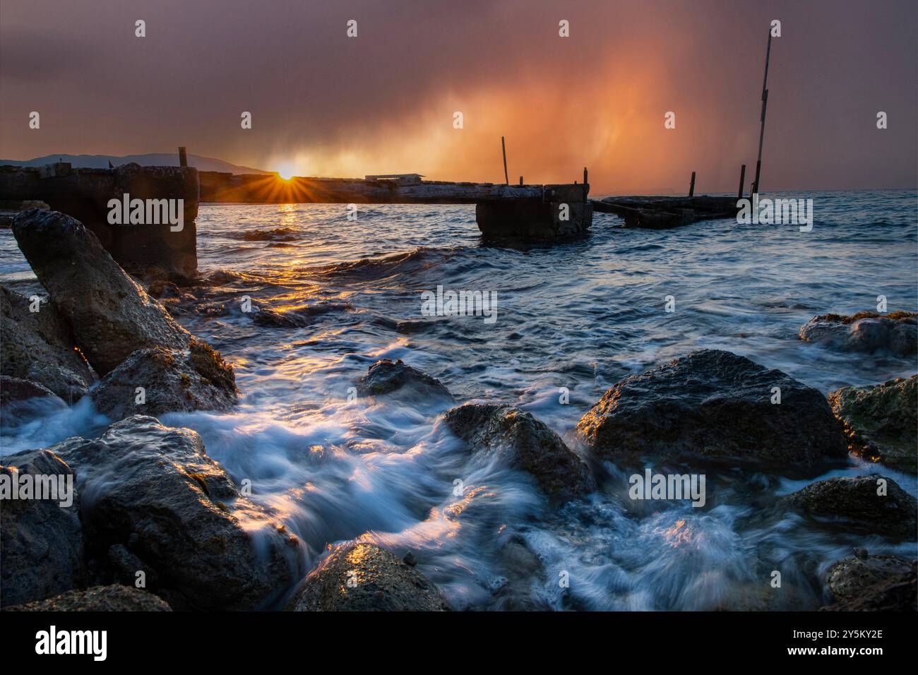 Une photographie longue exposition d'une jetée délabrée en Crète, Grèce avec une tempête de pluie menaçant au loin Banque D'Images