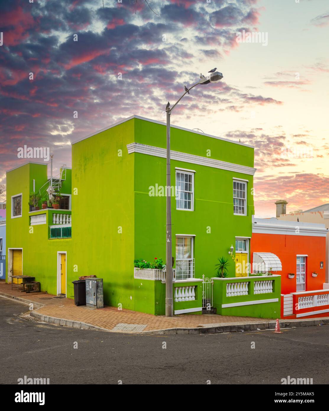 Bâtiments sur un coin, avec un ciel de coucher de soleil spectaculaire en arrière-plan, mettant en valeur la beauté architecturale et les teintes vibrantes dans la mélodie culturelle de Bo-Kaap Banque D'Images