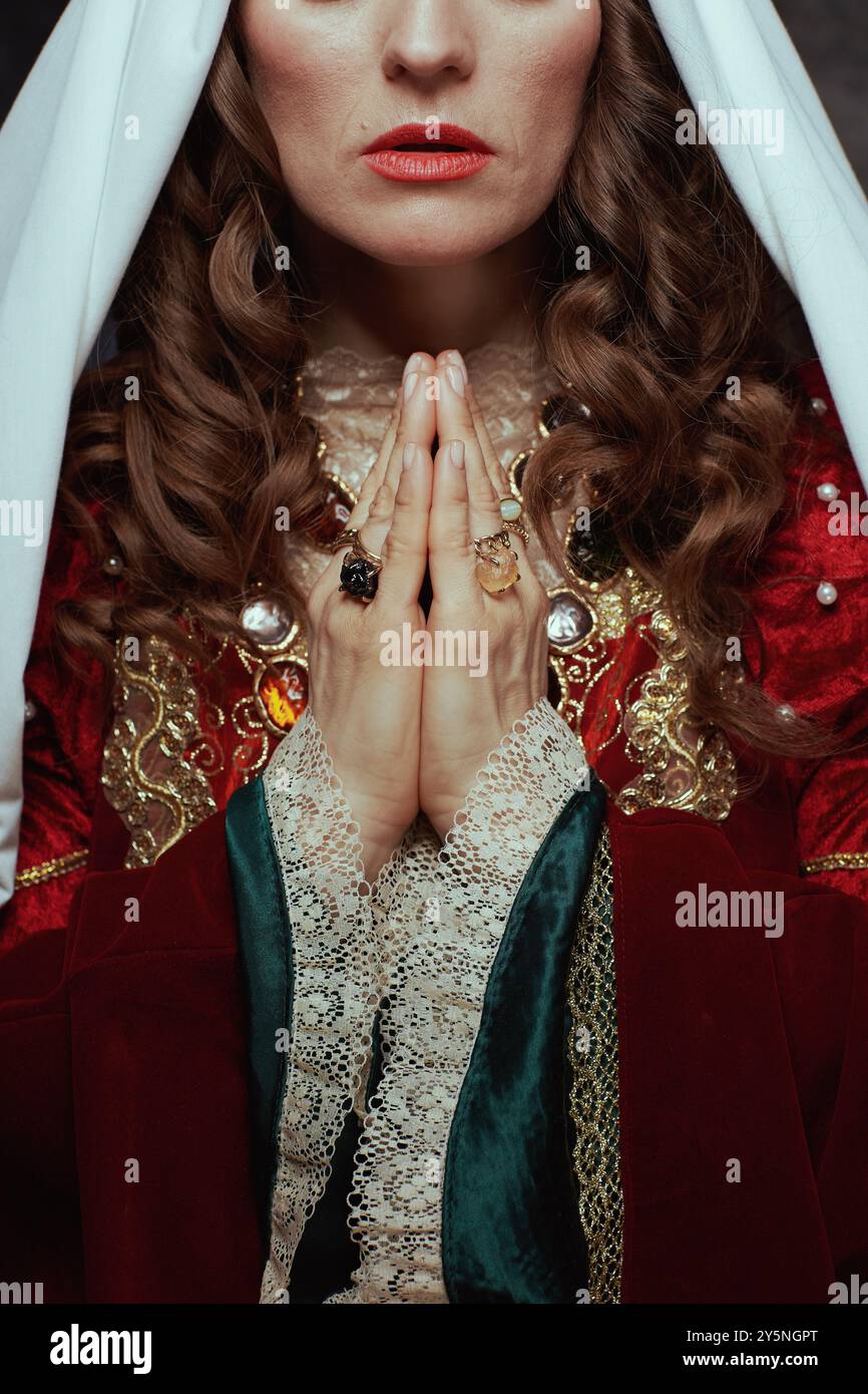 Gros plan sur la reine médiévale en robe rouge avec voile priant. Banque D'Images