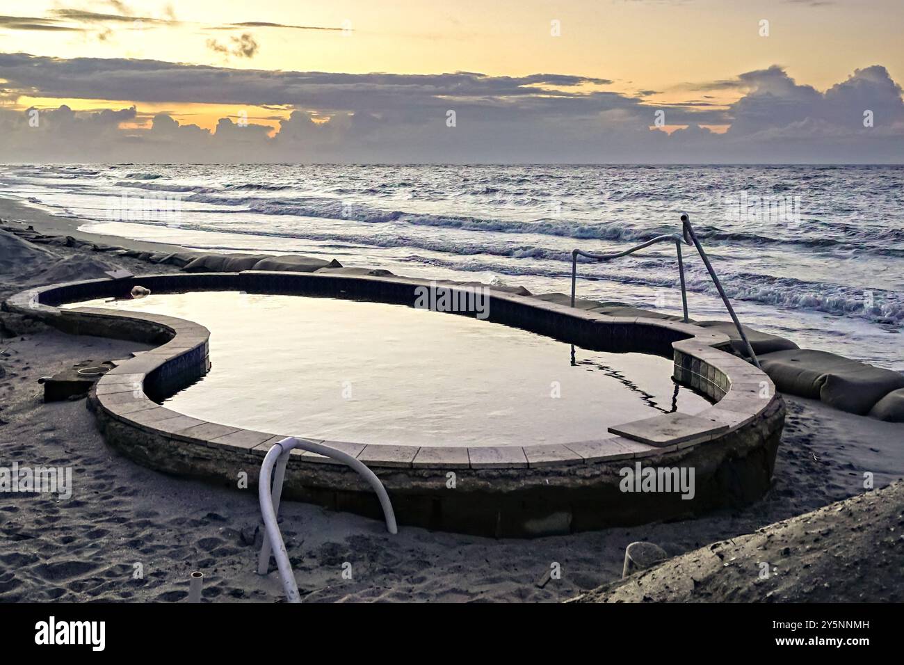 Île de Palms, États-Unis. 05 mai 2024. Une piscine dans une résidence en bord de mer avec les marées de l'océan Atlantique approchant et érodant le sable malgré des sacs de sable d'urgence qui étayent la région à Wild Dunes, le 5 mai 2024 à Isle of Palms, Caroline du Sud. Le changement climatique provoque des marées plus élevées et plus fortes qui enlèvent des centaines de pieds des plages le long de la région de basse campagne. Crédit : Richard Ellis/Richard Ellis/Alamy Live News Banque D'Images