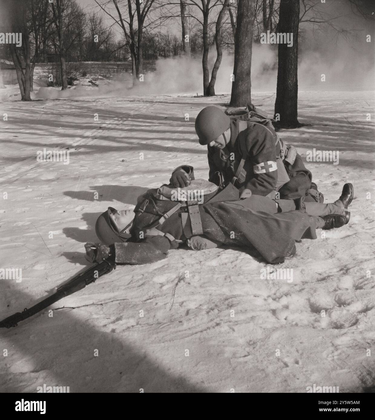 L'Amérique des années 1940 Photo vintage de la manifestation devant les médecins de l'armée et les candidats officiers à l'école de service de l'armée américaine. Trois hommes d'aide de compagnie (soldats médicaux non armés), sont attachés à chaque compagnie d'infanterie ainsi qu'à d'autres unités de combat, et se déplacent avec eux dans le champ de bataille. Quand un blessé tombe, il administre les premiers soins et met une étiquette sur sa baïonnette pour que les porteurs de litière trouvent. Carlisle, Pennsylvanie. Février 1943 Banque D'Images