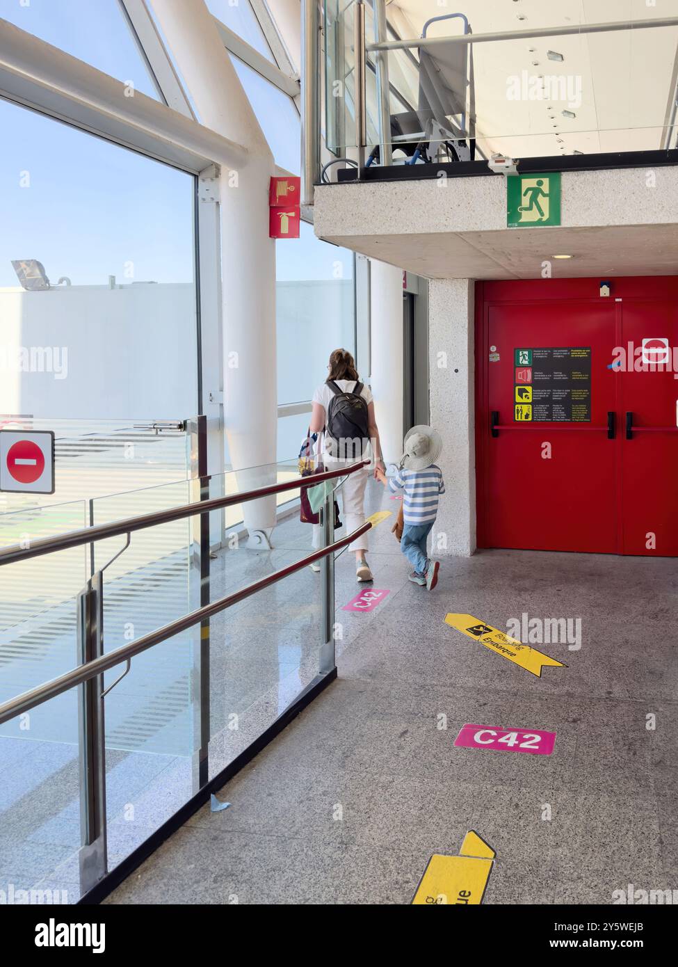 Palma, Espagne, 11 juillet 2024 : une image verticale d'une mère et de son fils marchant à l'intérieur de l'aéroport PMI, suivant plusieurs flèches de guidage sur le sol Banque D'Images