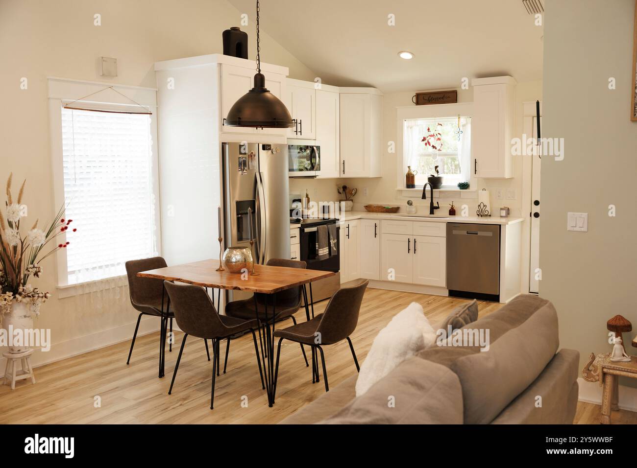 Intérieur de cuisine moderne avec armoires blanches, appareils en acier inoxydable et une table à manger en bois éclairée par une grande suspension, Floride, États-Unis Banque D'Images