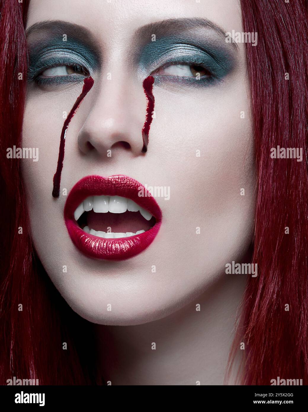 Femme avec les cheveux roux et le maquillage dramatique, y compris le rouge à lèvres rouge bavé Banque D'Images