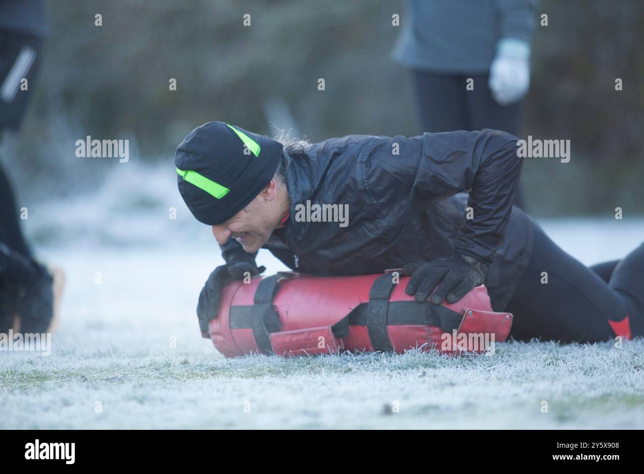 Personne effectuant la RCP sur un mannequin de formation à l'extérieur sur de l'herbe givrée avec une autre personne en arrière-plan. Banque D'Images