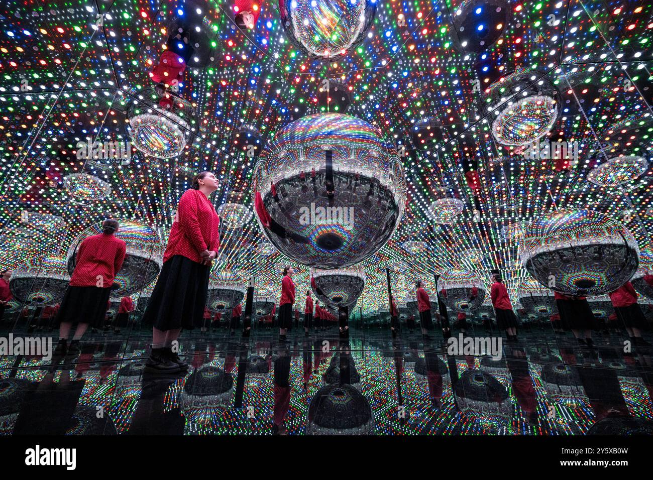 Londres, Royaume-Uni. 23 septembre 2024. Un membre du personnel lors d’une avant-première de « Every Day I Pray for Love », la quatorzième exposition personnelle de Yayoi Kusama avec la galerie Victoria Miro présentant la dernière série de peintures et sculptures de l’artiste et une nouvelle salle en miroir Infinity appelée « beauté décrite par un cœur sphérique », 2024, (photo). L’exposition se déroule à la galerie Wharf Road de Victoria Miro du 25 septembre au 2 novembre 2024. Credit : Stephen Chung / Alamy Live News Banque D'Images