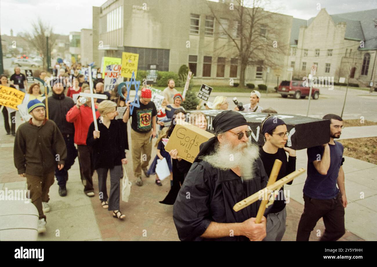 Les manifestants anti-guerre défilent à travers Bloomington, Indiana, portant des signes et des symboles de paix lors d'une manifestation contre l'implication des États-Unis dans les guerres en Afghanistan et en Irak. Les participants tiennent des croix, des signes de paix et des banderoles appelant à la fin de la violence, reflétant l'opposition généralisée aux actions militaires de l'administration Bush. Banque D'Images