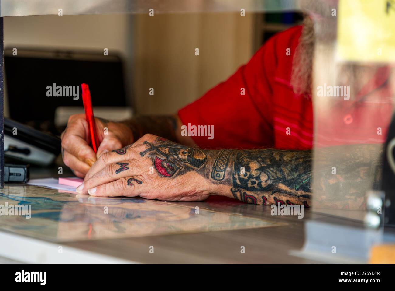 Vendeur avec des tatouages de bras à la billetterie pour une excursion en bateau à travers le Schlei, Kappeln. Commis tatoué. AM Hafen, Kappeln, Schleswig-Holstein, Allemagne Banque D'Images