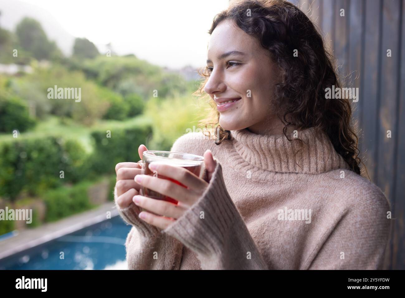 Femme souriante tenant une tasse de thé, se détendre à la maison avec vue panoramique Banque D'Images