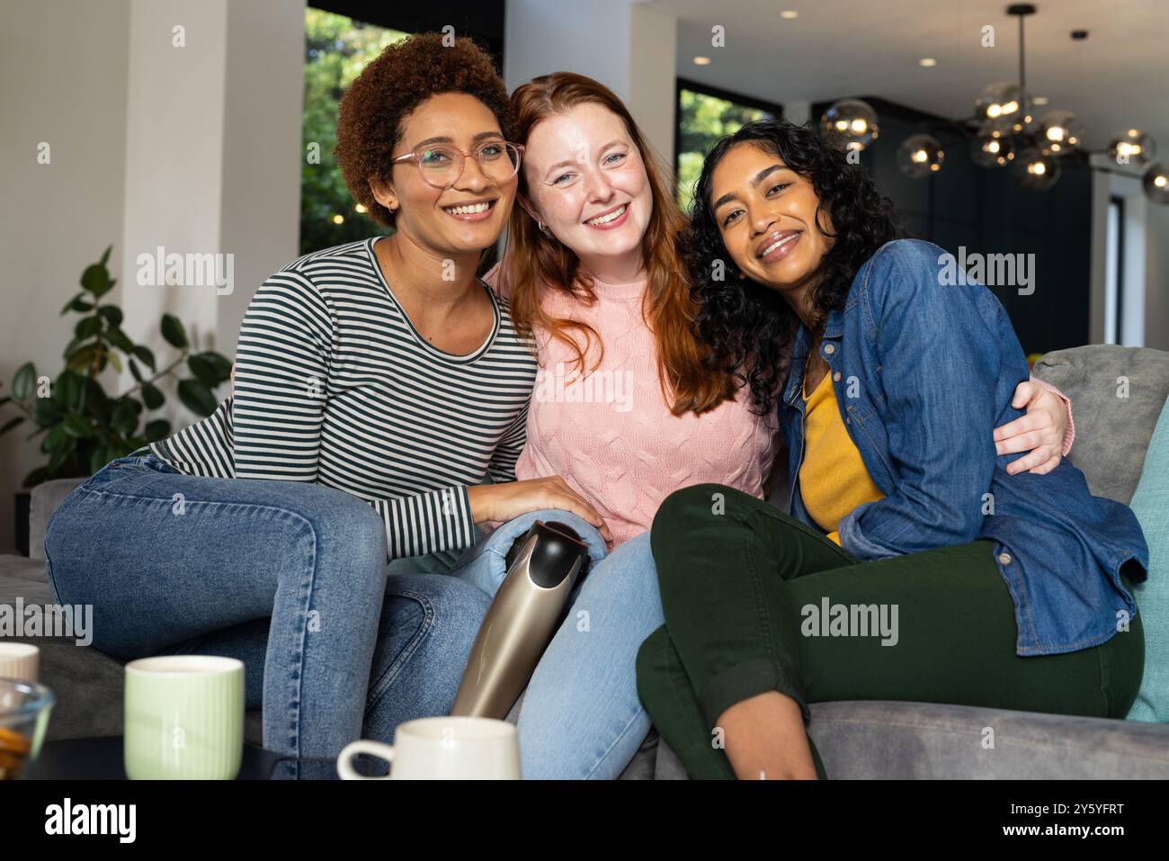 Souriant diverses femmes amis assis sur le canapé, appréciant le café et passant du temps ensemble Banque D'Images