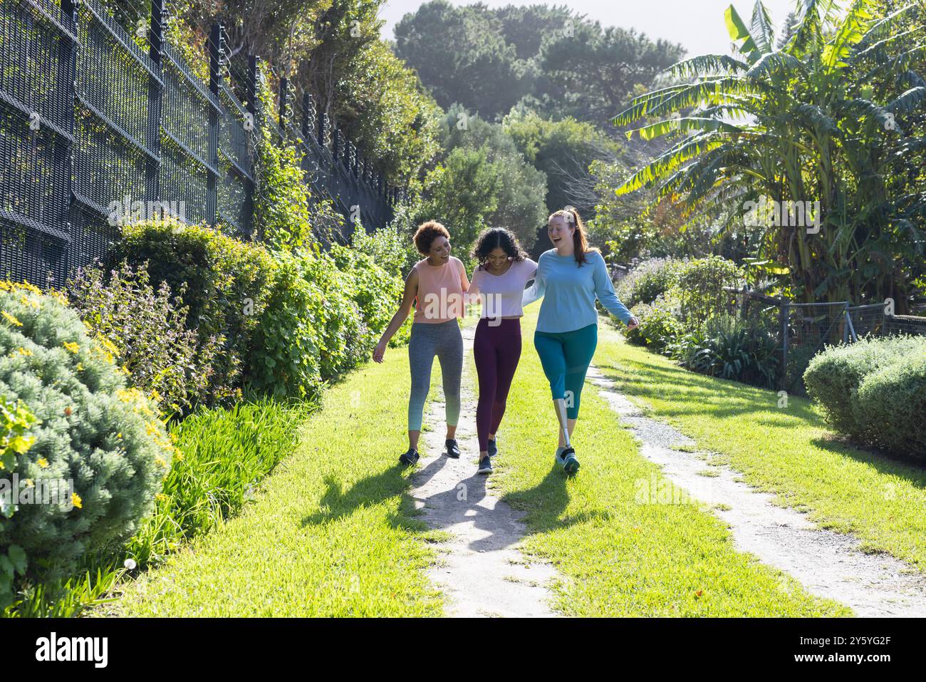 Marchant ensemble à l'extérieur, diverses femmes amies appréciant la nature et les liens dans le parc Banque D'Images