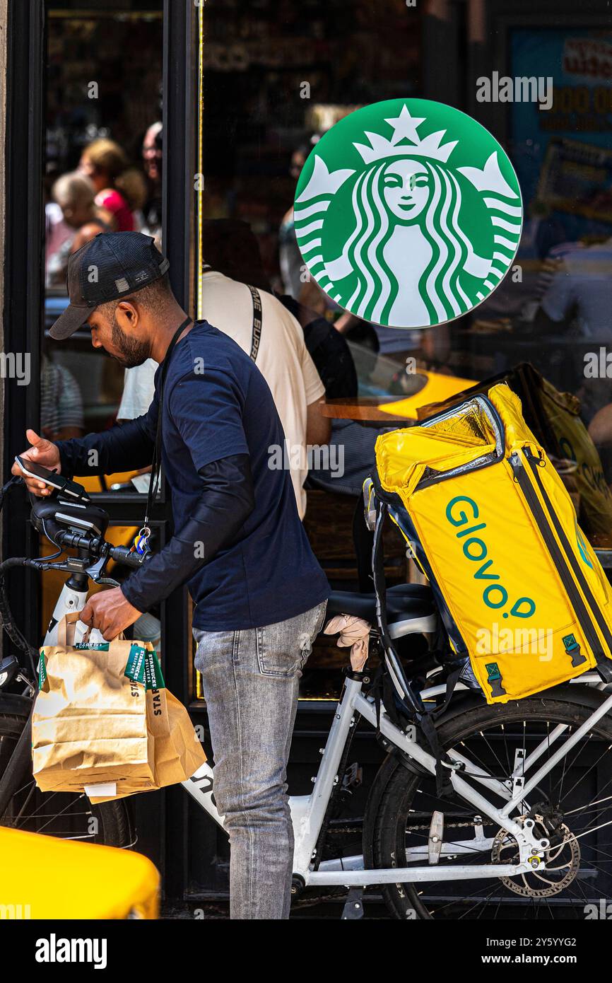 Cavalier de glovo devant Starbucks. La Rambla de Barcelona. Banque D'Images