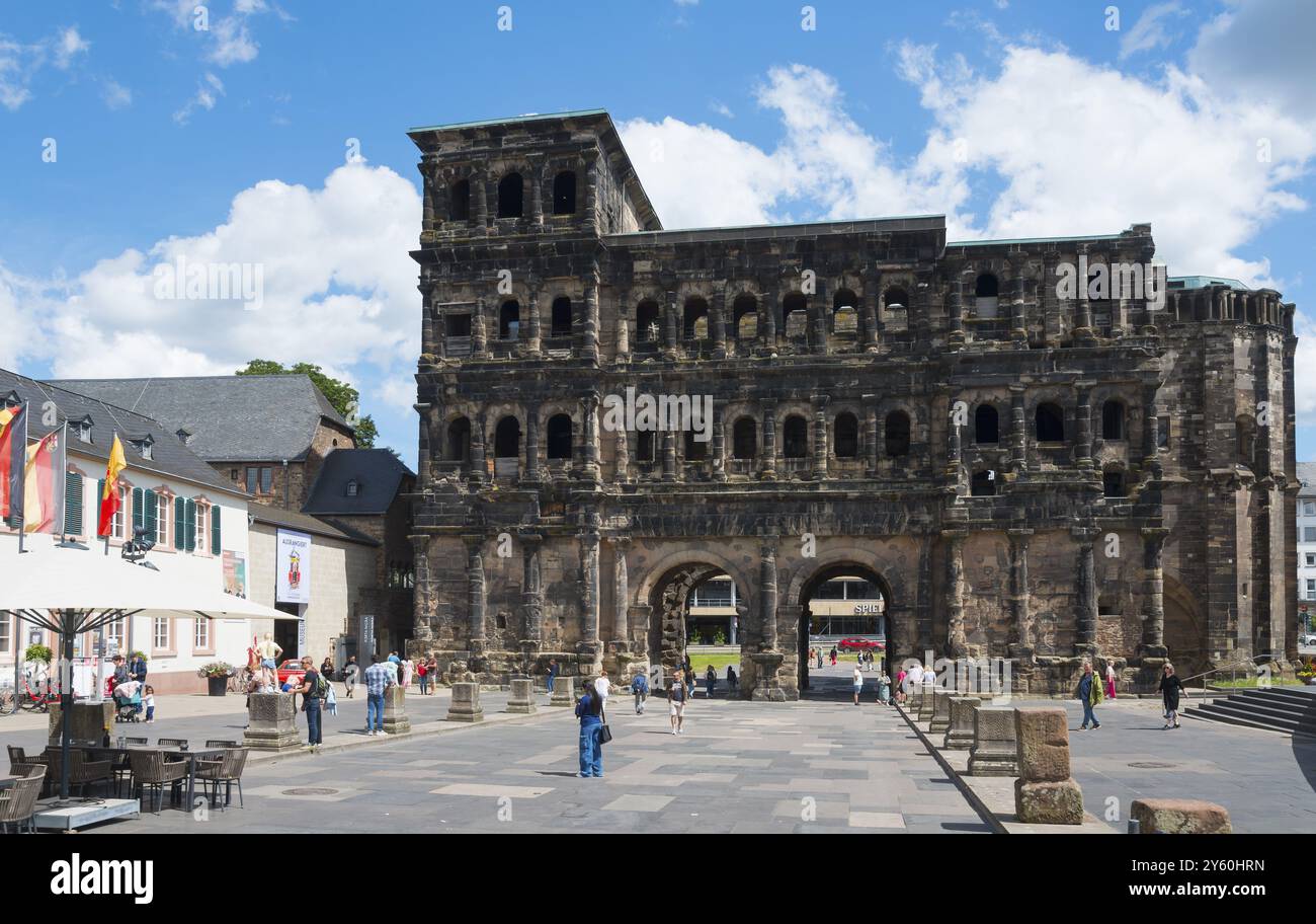 Un grand bâtiment ancien avec plusieurs arches et fenêtres, entouré de gens sur une rue ensoleillée, Porta Nigra, porte Noire, porte romaine de la ville, Trèves, RH Banque D'Images