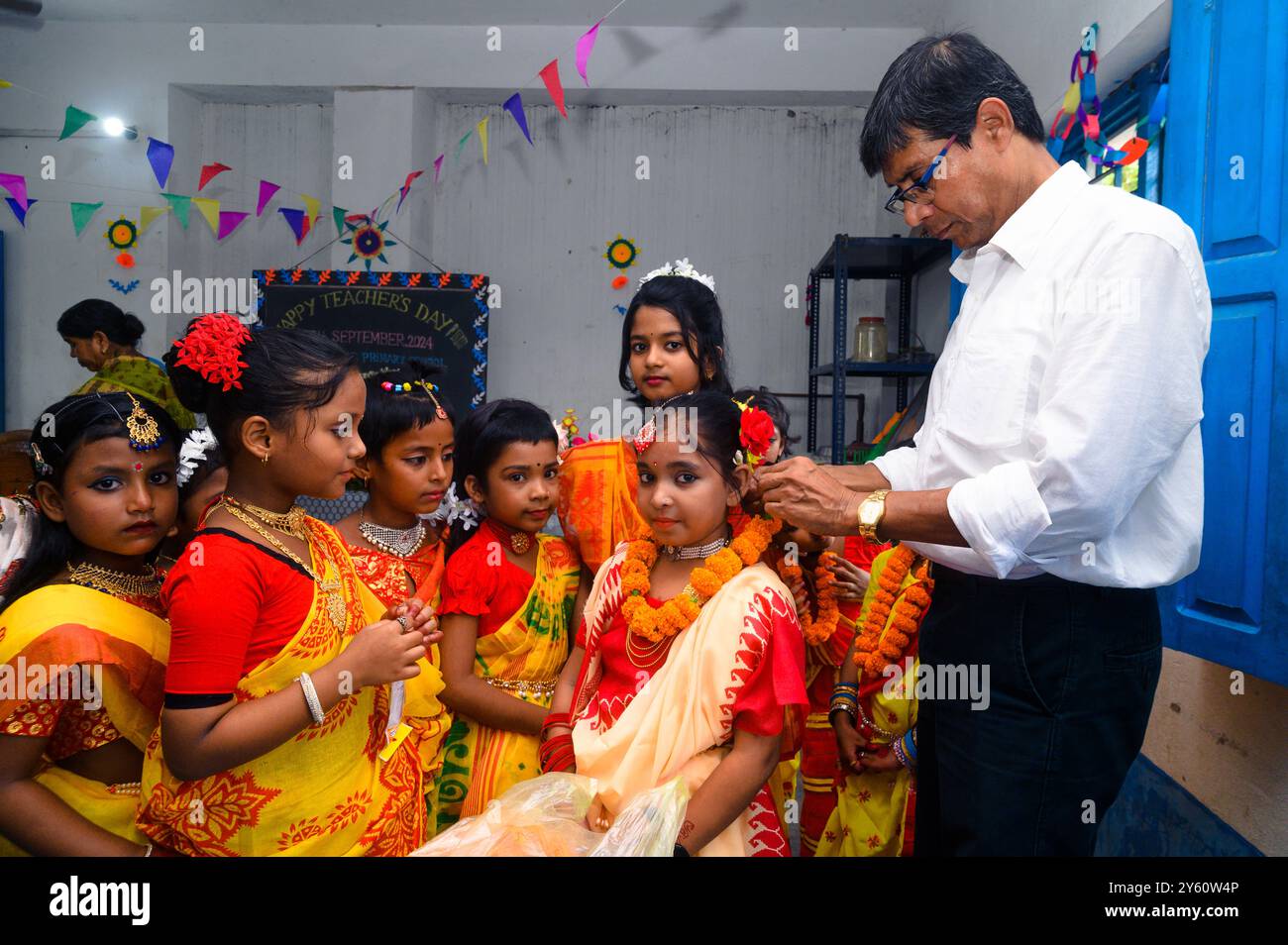 L'école primaire Nabin Nagar est une école rurale éloignée située à Nabin Nagar, le long de la frontière entre l'Inde et le Bangladesh. Malgré les défis, l'école célèbre la Journée des enseignants le 5 septembre, marquant l'anniversaire du Dr Sarvepalli Radhakrishnan, le deuxième président de l'Inde. Le directeur de l'école prend l'initiative d'organiser la célébration, en préparant des guirlandes de fleurs de souci pour ses étudiantes avant leur performance de danse. Nabin Nagar, Bengale occidental, Inde. Banque D'Images