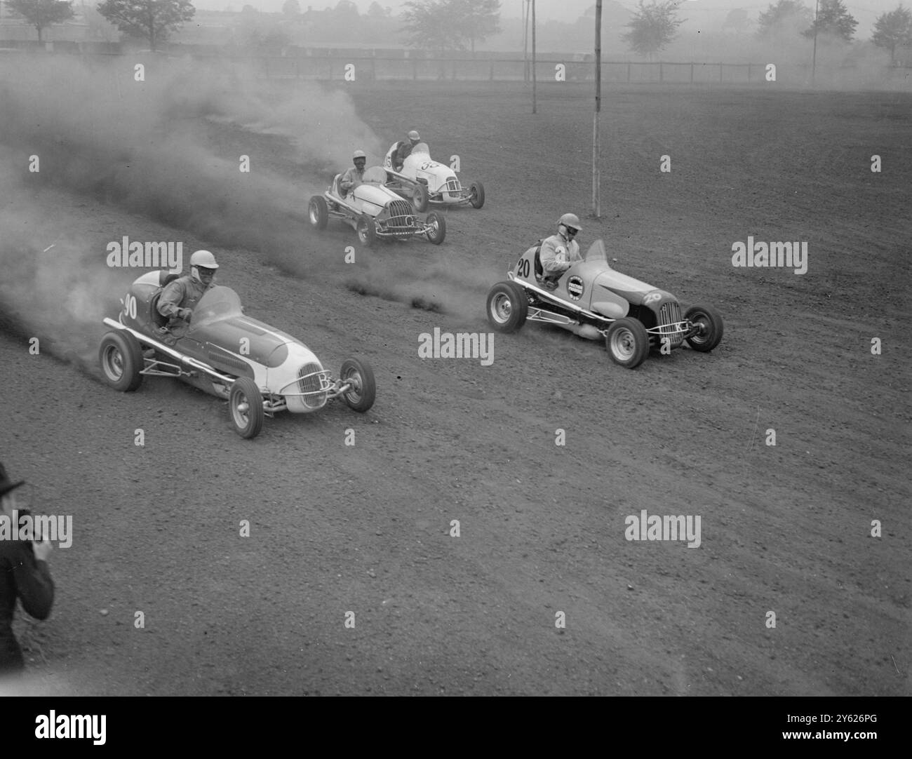 « MIDGETS DEBUT » À WALTHAMSTOW LES PILOTES DE COURSE S'ENTRAÎNENT. Occupés à s'échauffer pour leurs prochains « débuts » à Londres, les pilotes des voitures de course midget américaines ont essayé aujourd'hui leurs « puissants atomes » au stade de Walthamstow. Les voitures peuvent toucher 80 m.p.h. L'IMAGE MONTRE:- ' petit mais bon ' membres de l'équipe américaine de voitures midget à la vitesse lors des essais au stade de Walthamstow aujourd'hui. 10 mai 1948 Banque D'Images
