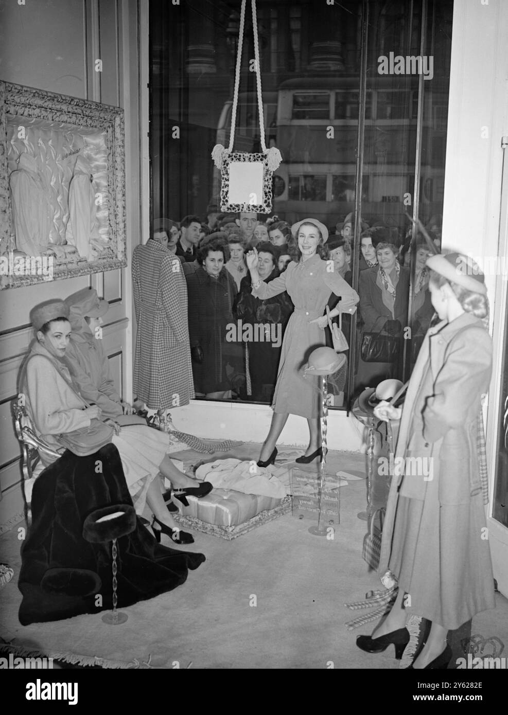 Les acheteurs le long de Regent Street ont eu quelque chose de choquant aujourd'hui, alors qu'ils regardaient la mode londonienne intelligente. Au lieu des mannequins de cire habituels, la maison de couture de Wetherall avait d'élégants modèles « chair et sang » affichant leurs manteaux « Fourway » dans la fenêtre. L'image montre : « est-ce que celui-là a bougé ? ». Une foule se rassemble à la vitrine tandis que les mannequins organisent une exposition de « mannequins » dans la boutique de Regent Street de Wetherall. 22 janvier 1948 Banque D'Images