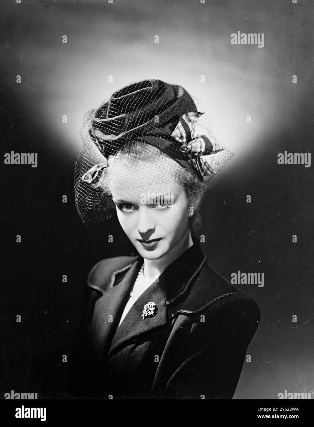 Ce petit chapeau gay, annonçant le printemps, est fabriqué à partir de feutre de fourrure pastel astucieusement plié. Le taffetas tartan est utilisé pour les arcs soucoupes de chaque côté, et une touche sophistiquée est ajoutée par le voile. 18 janvier 1948 Banque D'Images