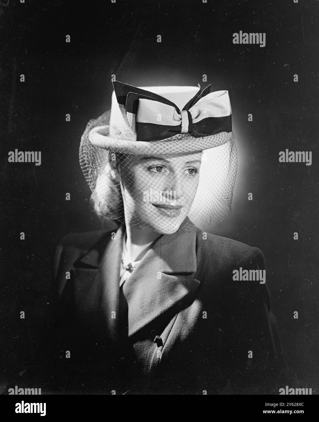 Ce chapeau de marin, qui rappelle les vieux jours de la voile, est façonné en feutre beige et a un bord de ballon. Un grand noeud en petersham noir et beige fait une décoration accrocheuse, et une touche finale d'intelligence est ajoutée par le voile noir. 18 janvier 1948 Banque D'Images