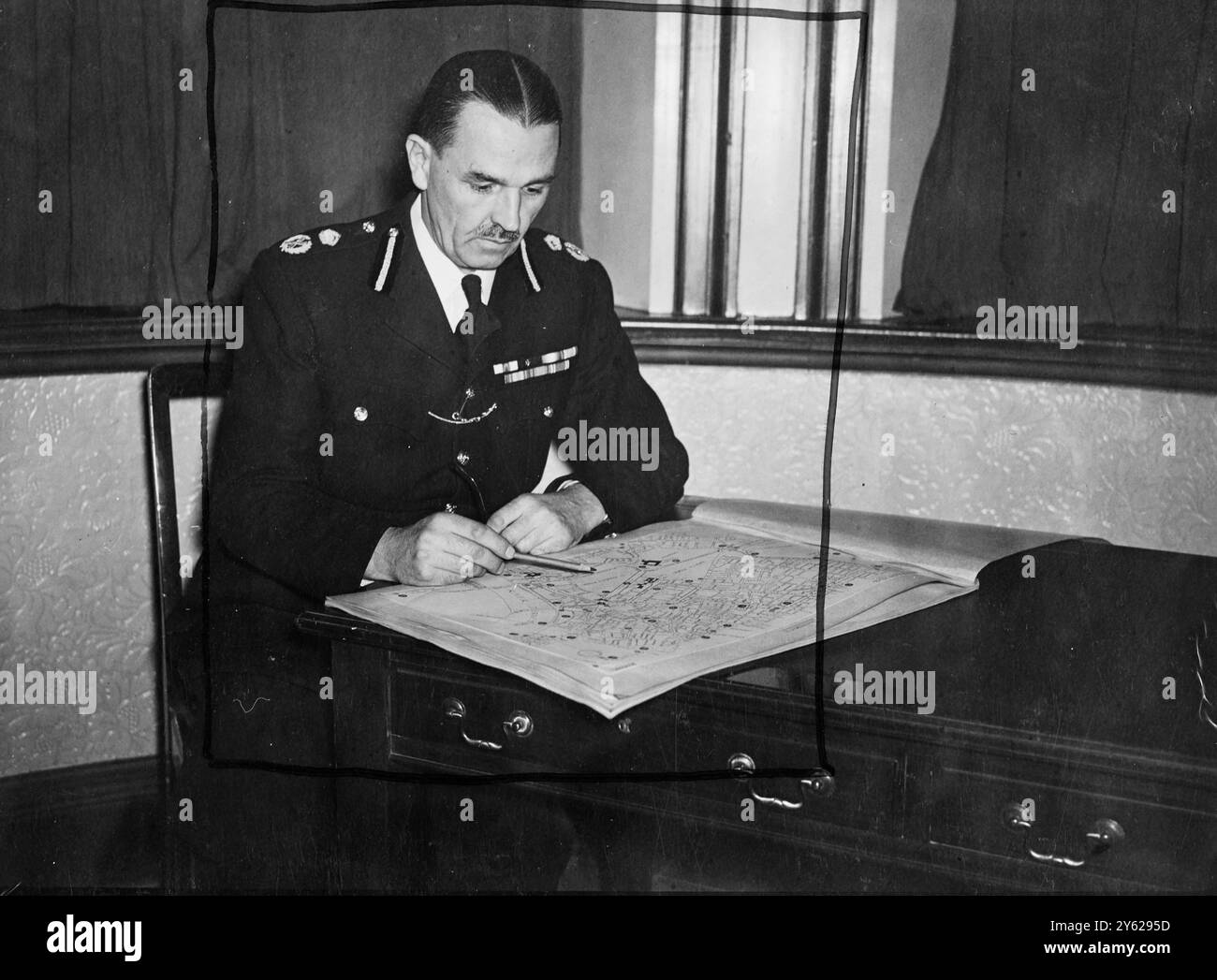 Un homme avec une responsabilité colossale opérera dans les coulisses du mariage royal de demain. Il est le major P.R. Margetson, M.C. de Scotland Yard, dans les mains duquel se trouvent les arrangements policiers généraux pour la grande occasion de demain. Des mesures de précaution complètes ont été prises le long des itinéraires. Les policiers ont été informés avec des descriptions et des photographies de produits indésirables, les égouts et les passages souterrains ont fait l'objet d'une enquête approfondie, et les arrangements de circulation autour de la zone vitale ont été organisés. La photo montre le major étudiant une carte de la route du mariage royal dans son bureau à Scotl Banque D'Images