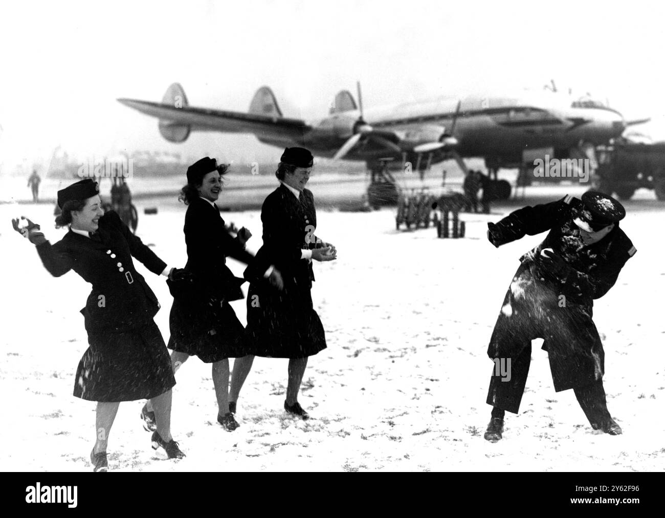 La neige profonde sur l'aérodrome et les conditions météorologiques défavorables ont paralysé les vols à l'aéroport de Londres ( Heathrow ) . Ici, un groupe d'hôtesses de l'air de la BOAC et le personnel au sol effectuent une attaque massive de boule de neige sur le surintendant adjoint de la station M. E. Lewis , au cours d'une bataille à l'heure du déjeuner . 30 janvier 1947 Banque D'Images