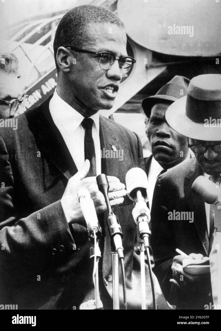 Malcolm X installera le QG à Washington : Malcolm X, un dirigeant de l'Organisation des musulmans noirs, photographié en train d'être interrogé à son arrivée à l'aéroport national de Washington, le 9 mai 1963, en provenance de New York, pour établir le siège dans la capitale nationale. Il a déclaré que les musulmans parraineront une série de réunions exclusivement noires visant à résoudre les problèmes de criminalité du district de Columbia. Il a dit que les musulmans, une secte extrémiste, ne prêchaient pas la haine. Banque D'Images
