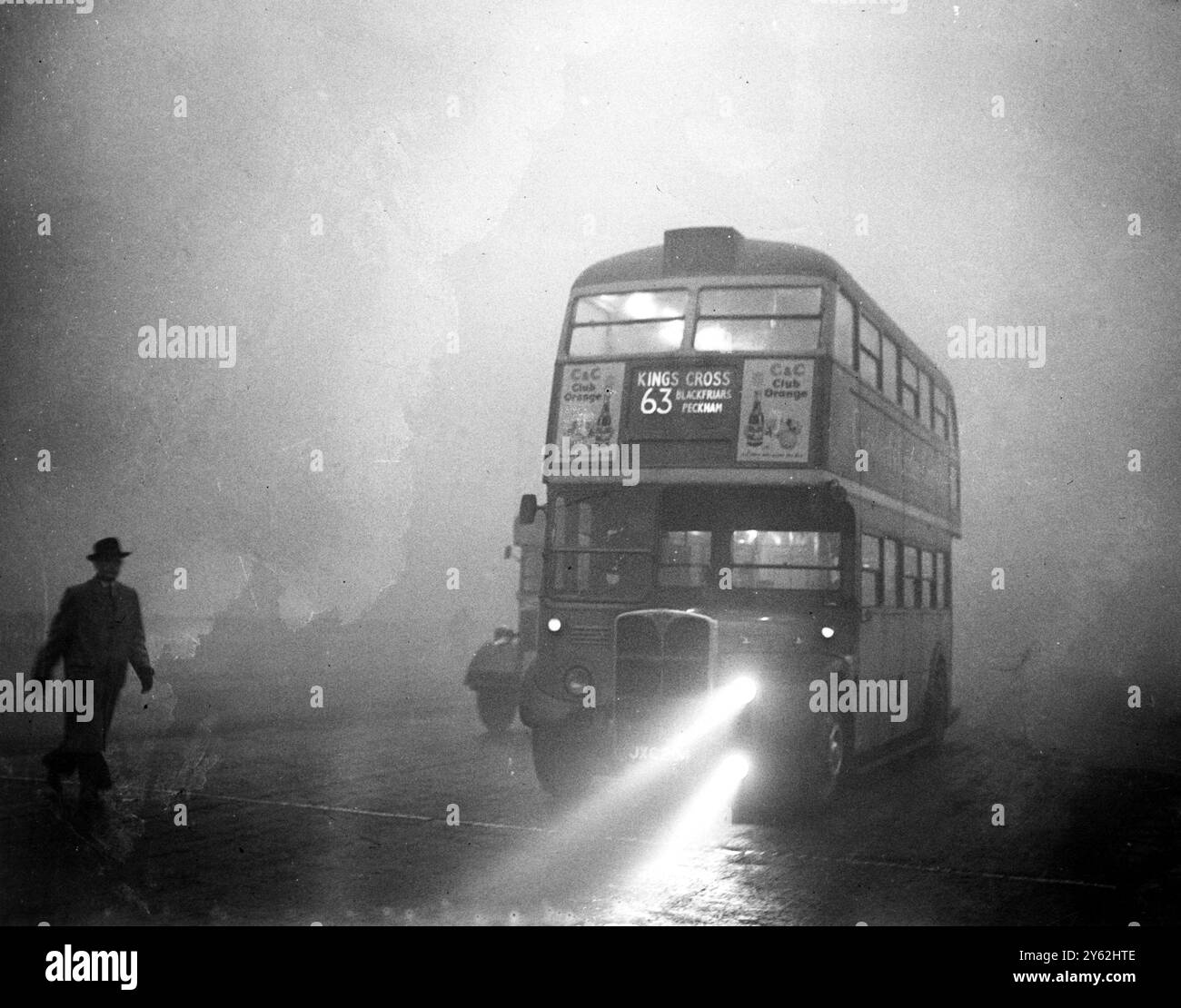 Une couverture de brouillard qui couvrait Londres amena le trafic routier et ferroviaire à une rampante et arrêta les navires et les avions. De nombreux passagers dans les véhicules publics ont dû marcher et, dans certains cas, ont aidé les conducteurs le long en marchant devant avec des torches allumées et des balises. Image montre : Un bus bien guidé par ses phares antibrouillard rampant le long du remblai dans le black-out . 6 décembre 1952 Banque D'Images