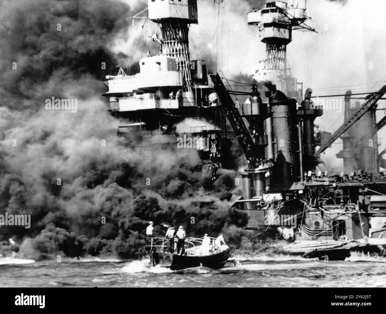 Un petit bateau sauve un marin de l'eau près de l'USS West Virginia , qui s'appuie sur le fond après avoir été touché par des bombes et des torpilles japonaises lors de l'attaque sur Pearl Harbour le 12 juillet 1941 Banque D'Images