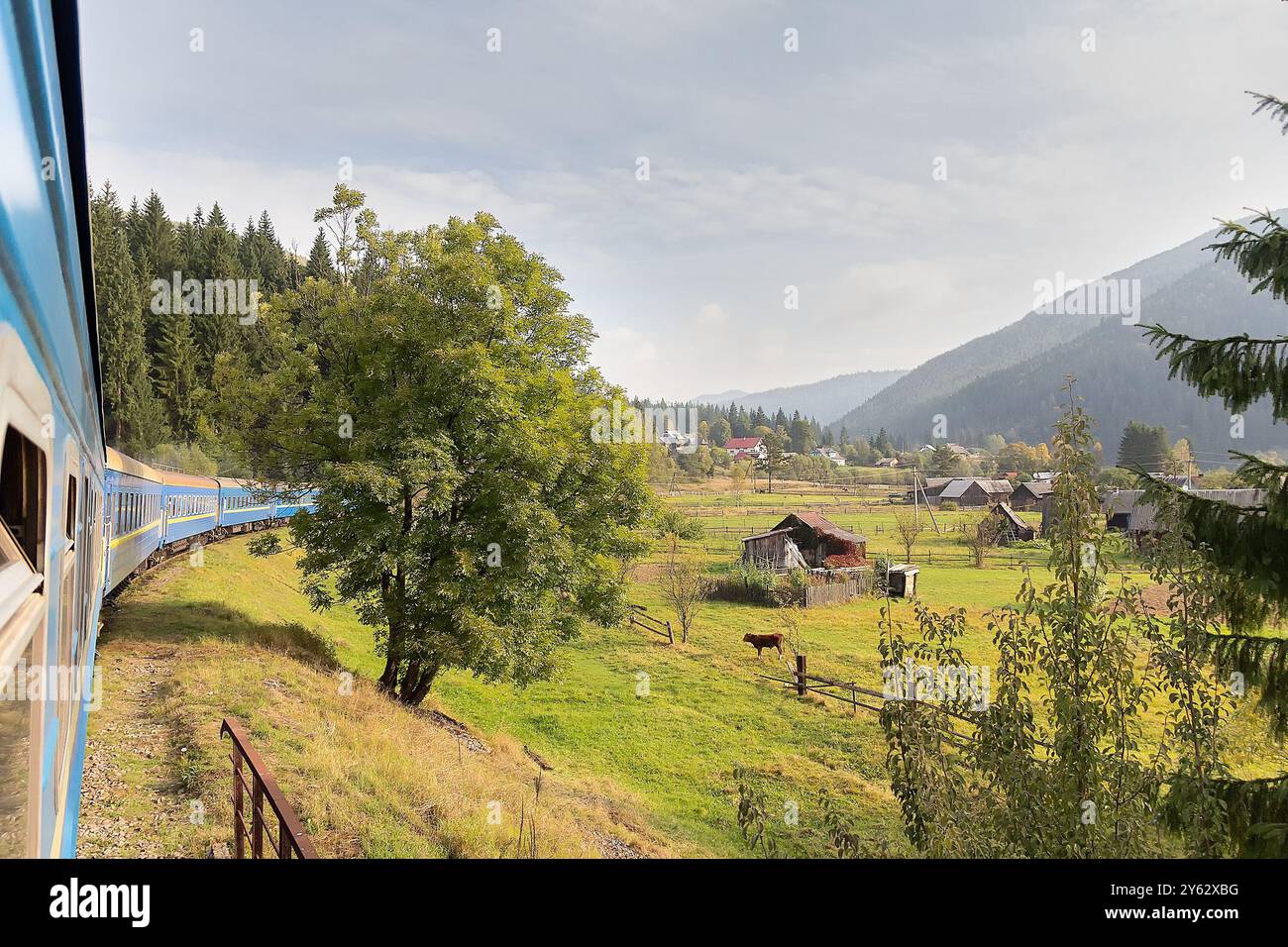 Vue depuis la fenêtre du train au village ensoleillé. Carpates, Ukraine Banque D'Images