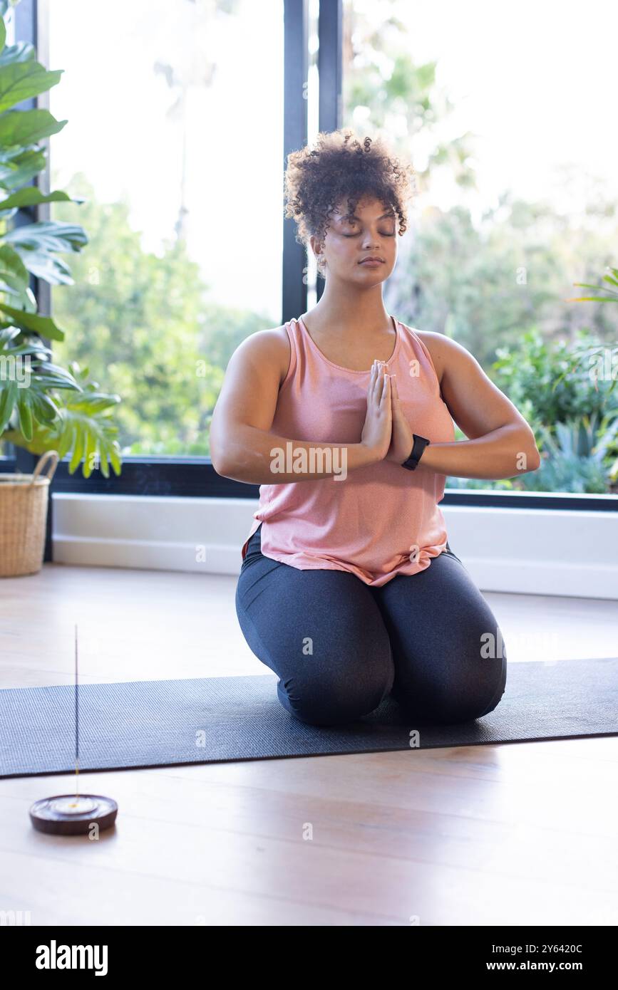 Pratiquer la pleine conscience à l'intérieur, femme grande taille méditant sur tapis de yoga, à la maison, à la maison Banque D'Images