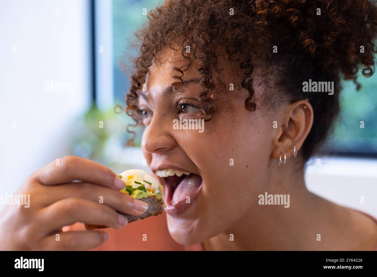 Manger une collation saine, femme appréciant des aliments nutritifs avec le sourire, à la maison, à la maison Banque D'Images