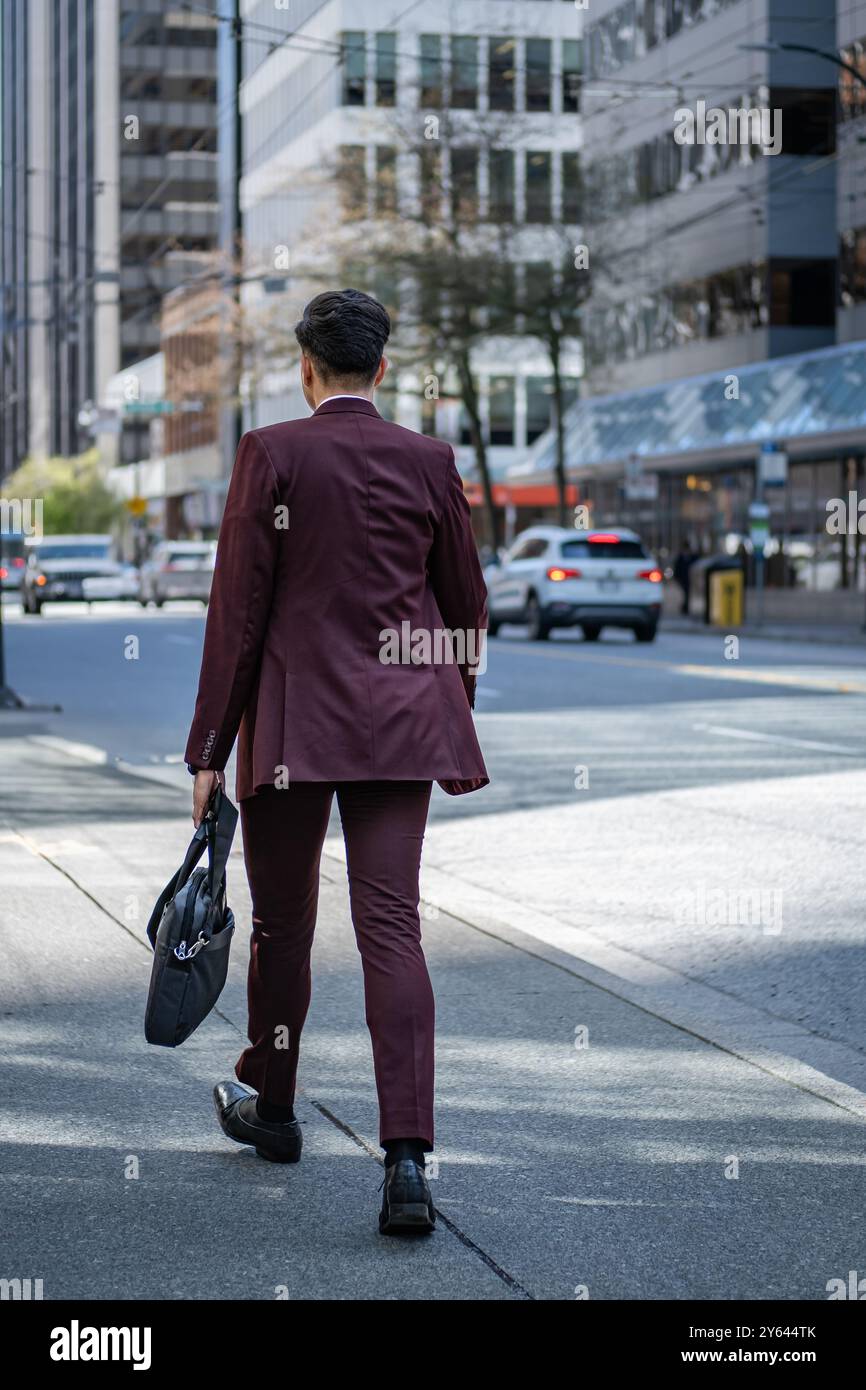 Homme d'affaires tenant une mallette et allant travailler. Homme en costume classique avec mallette marchant à l'extérieur. Jeune homme avec une mallette dans une hâte marchant vite Banque D'Images