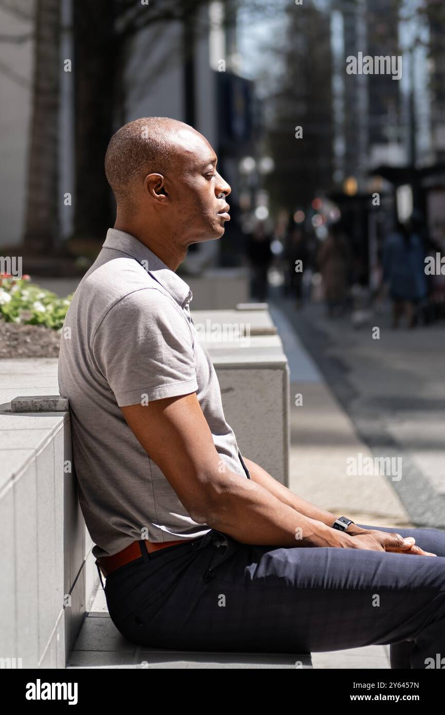 Homme afro-américain méditant en plein air faisant de la pratique de la respiration, assis dans un parc public avec les yeux fermés entraînement focus, concentration. Black Man relaxi Banque D'Images