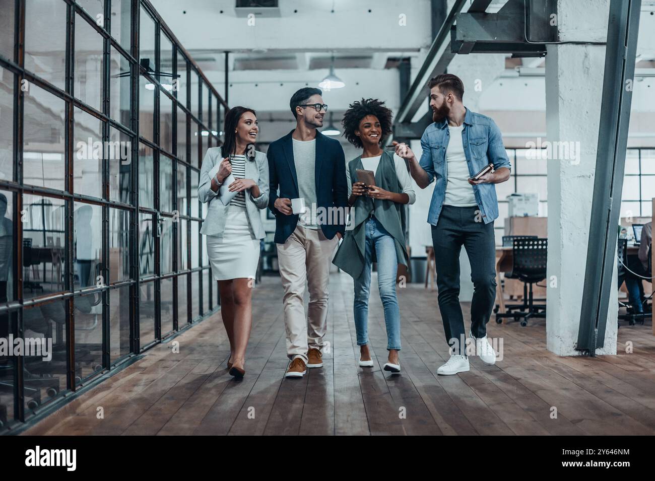 Des affaires créatives en déplacement. Toute la longueur des jeunes collègues dans le style décontracté élégant marcher et parler pendant une pause café au travail Banque D'Images