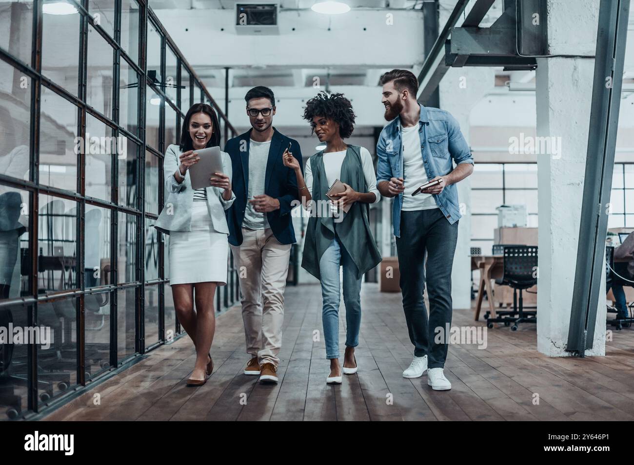 Prendre leur entreprise en déplacement. Pleine longueur de jeunes gens modernes dans des vêtements décontractés intelligents ayant une discussion tout en marchant à travers le grand moderne Banque D'Images