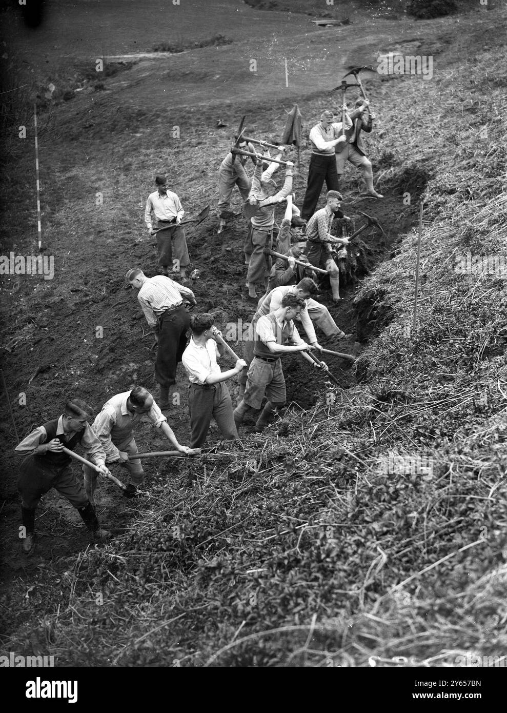 Quarante personnes - vingt anglaises et vingt allemandes - travaillent ensemble dans un camp de travail anglo-allemand qui se tient à l'école de Dauntsey , West Lavington , Wiltshire , Angleterre . Les membres du camp varient en âge entre 17 et 28 ans et comprennent des ouvriers d'usine et des étudiants universitaires. Le travail consiste à abattre des arbres , à niveler le sol et à faire des routes . Organisé conjointement avec le cercle anglo-allemand , le camp vise à une compréhension plus large entre toutes les sections des Nations anglaise et allemande . Vu ici des membres du camp se mettre en route avec des haches et des pelles pour un travail acharné. 9 Banque D'Images