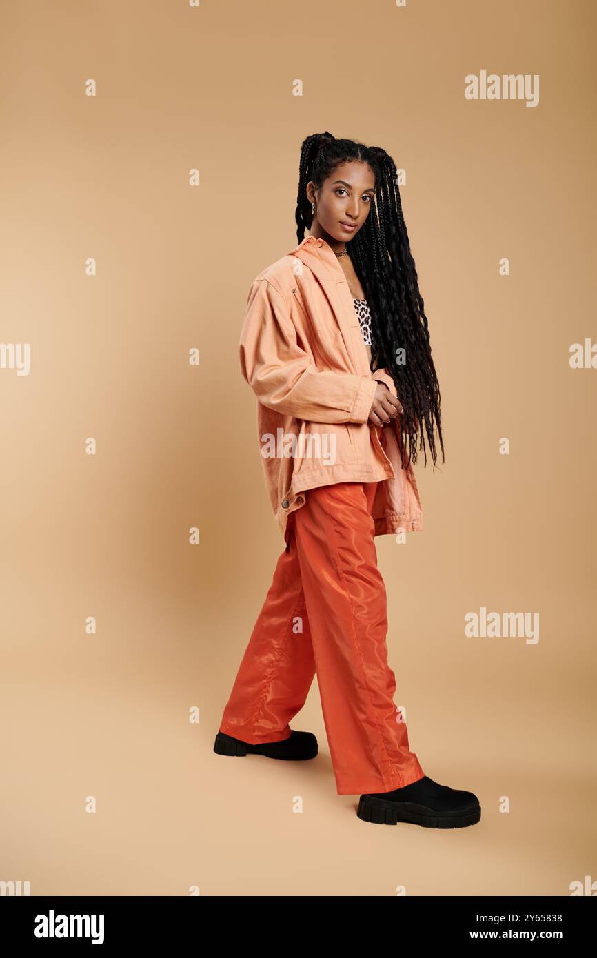 Dans une tenue chic, une jeune femme pose avec confiance, soulignant son look et son style avant-gardiste. Banque D'Images