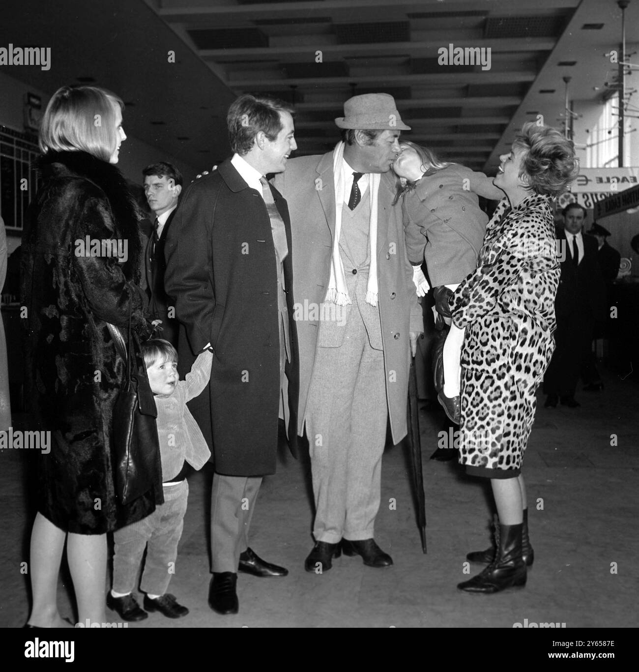 Rachel Roberts détient Cathryn Harrison, quatre ans, qui embrasse son grand-père et son mari, Rex Harrison, à l'aéroport de Londres. Le fils de Rex, Noel , la femme de Noel et le fils de Noel , Simon (2) avec Cathryn sont allés à l'aéroport pour saluer Rex et Rachel qui sont venus de Rome . 11 mars 1964 Banque D'Images