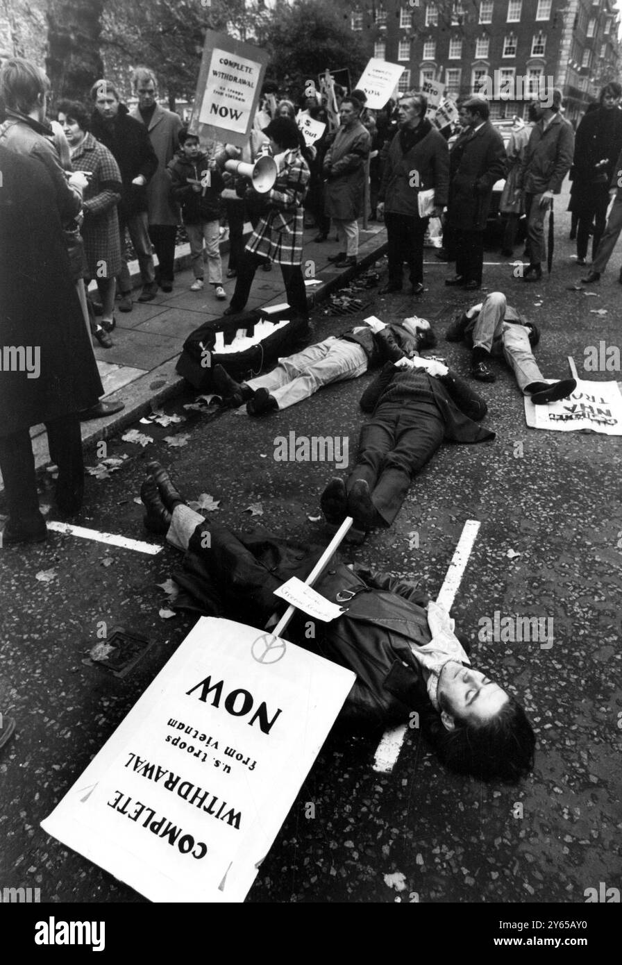 Manifestation contre la guerre du Vietnam de jeunes manifestants gisent sur la route de Grosvenor Square . Londres , feignant la mort au début d'une manifestation de six heures devant l'ambassade américaine contre la guerre du Vietnam . Les manifestants avec des pancartes de slogans anti-guerre placées à leurs côtés , avaient épinglé sur eux une grande carte blanche , avec le nom d'un américain tué au Vietnam . Sur le trottoir (centre-gauche) se trouve un cercueil dans lequel les cartes ont été déposées et qui sera ensuite présenté à l'ambassade. 15 novembre 1969 Londres Banque D'Images