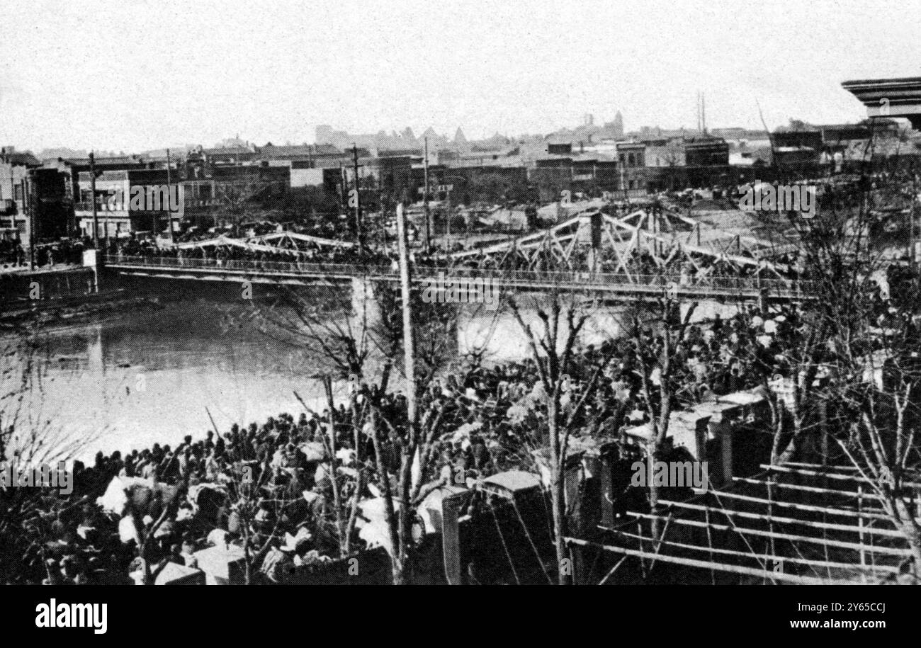 Alarme parmi la population chinoise de Tientsin à l'arrivée d'une forte force japonaise pour protéger les résidents japonais : foules traversant le pont sur la rivière dans les concessions étrangères . 1932 Banque D'Images