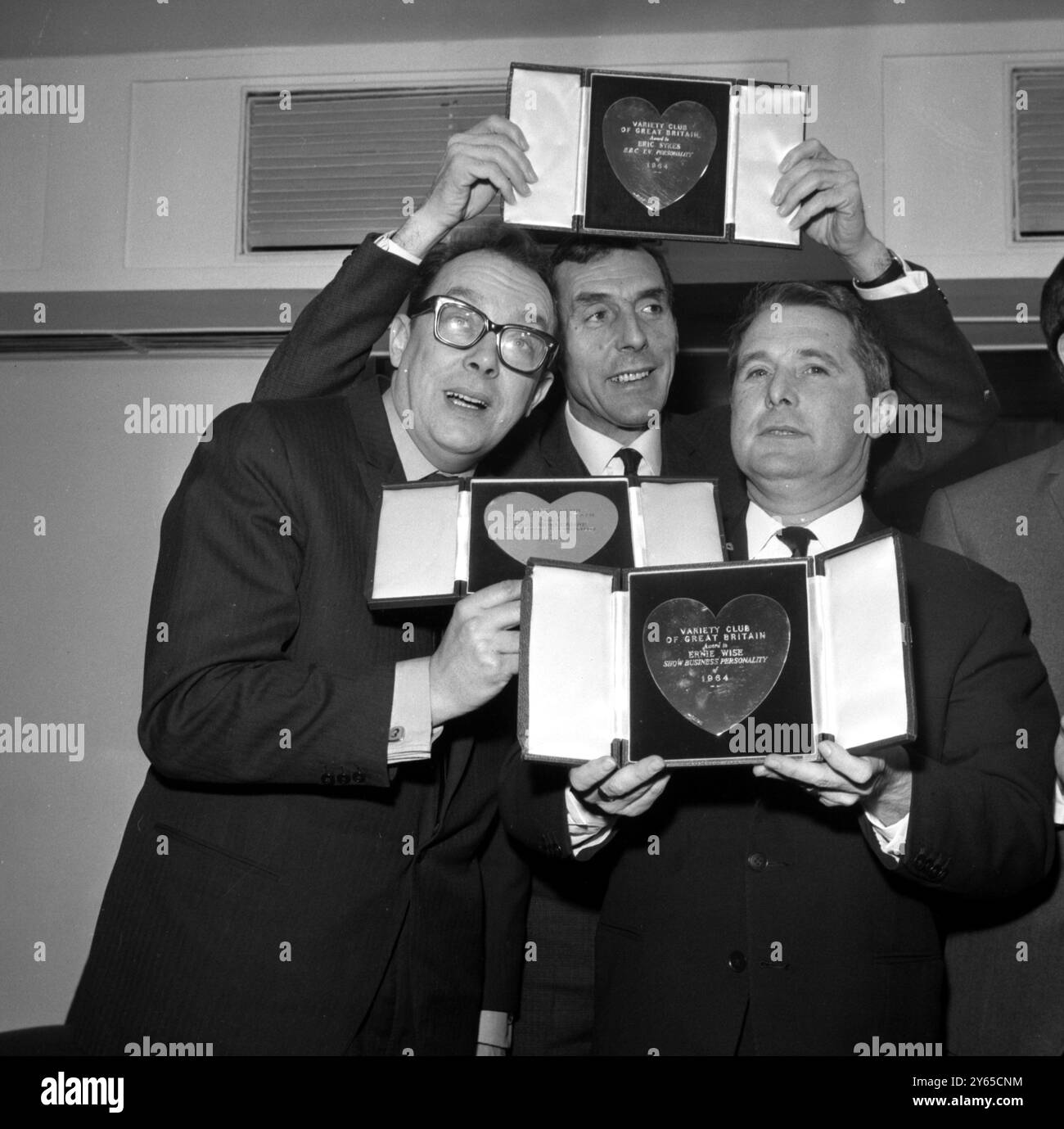 L'artiste Eric Sykes ( au centre ) semble être en train de guillotiner des partenaires de comédie, Eric Morcambe ( à gauche ) et Ernie Wise lors de leur rencontre heureuse à l'hôtel Savoy à Londres le 9 mars 1965 . Les trois E ont reçu le prix du Variety Club of Great Britain pour les meilleures étoiles de 1964. Morcambe et Wise ont été nommés conjointement « personnalités du show business de 1964 » et ont été cités pour « leurs succès à la télévision et à la radio », et Eric Sykes a été nommé « personnalité de la BBC TV » pour son programme « Sykes and a ... » Banque D'Images