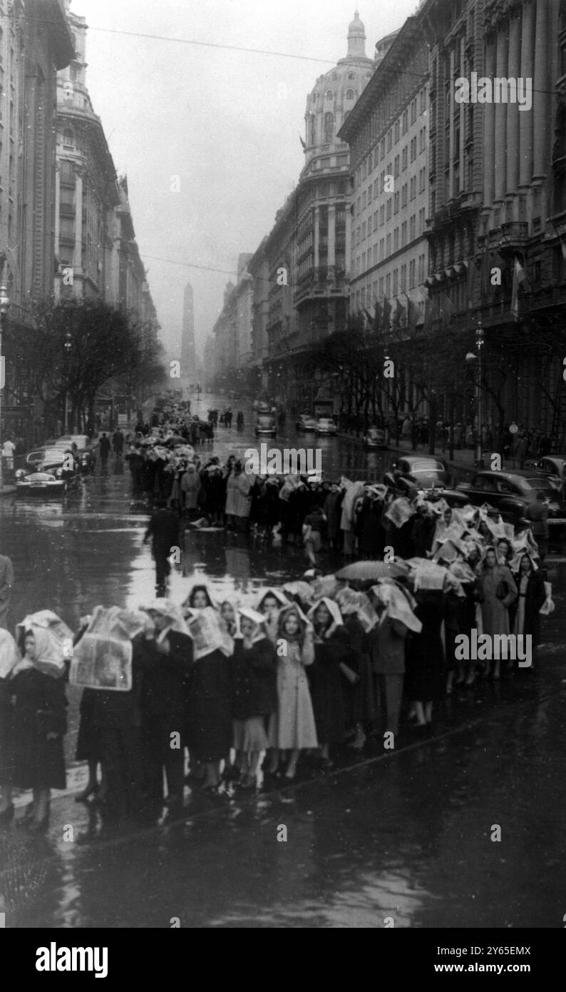 Mort d'Eva Peron se couvrant la tête de journaux contre la pluie battante , l'une des nombreuses files d'attente attendant patiemment de voir le corps d'Eva Peron gisant dans l'état au Ministère du travail et de la prévoyance sociale . Plus de 100 000 , dans plusieurs files d'attente , attendaient quand cette photo a été faite . 1er août 1952 Banque D'Images