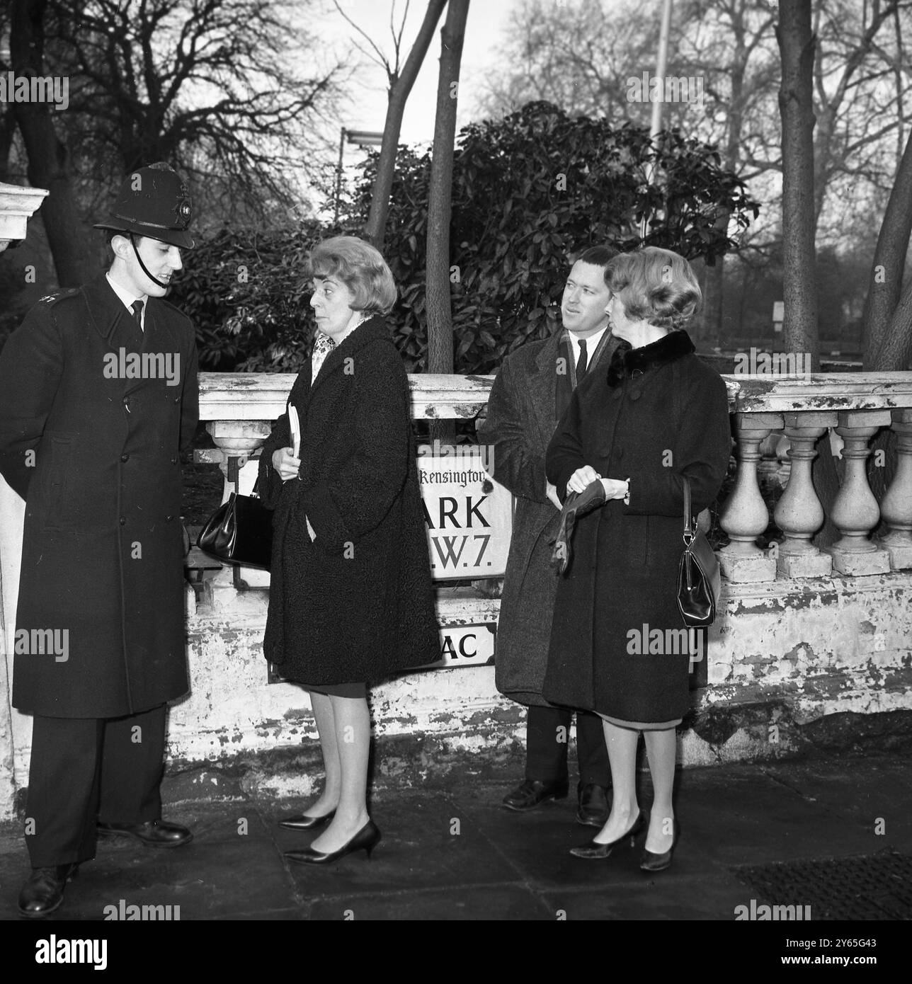 Intérêt américain pour Sir Winston Miss A Jilson ( à gauche ) de Miami , Floride , USA , est montré au coin de Hyde Park Gate à Londres interrogeant un policier sur la santé de l'homme d'État aîné et bien-aimé de Grande-Bretagne , Sir Winston Churchill qui réside dans la route . 23 janvier 1965 Banque D'Images