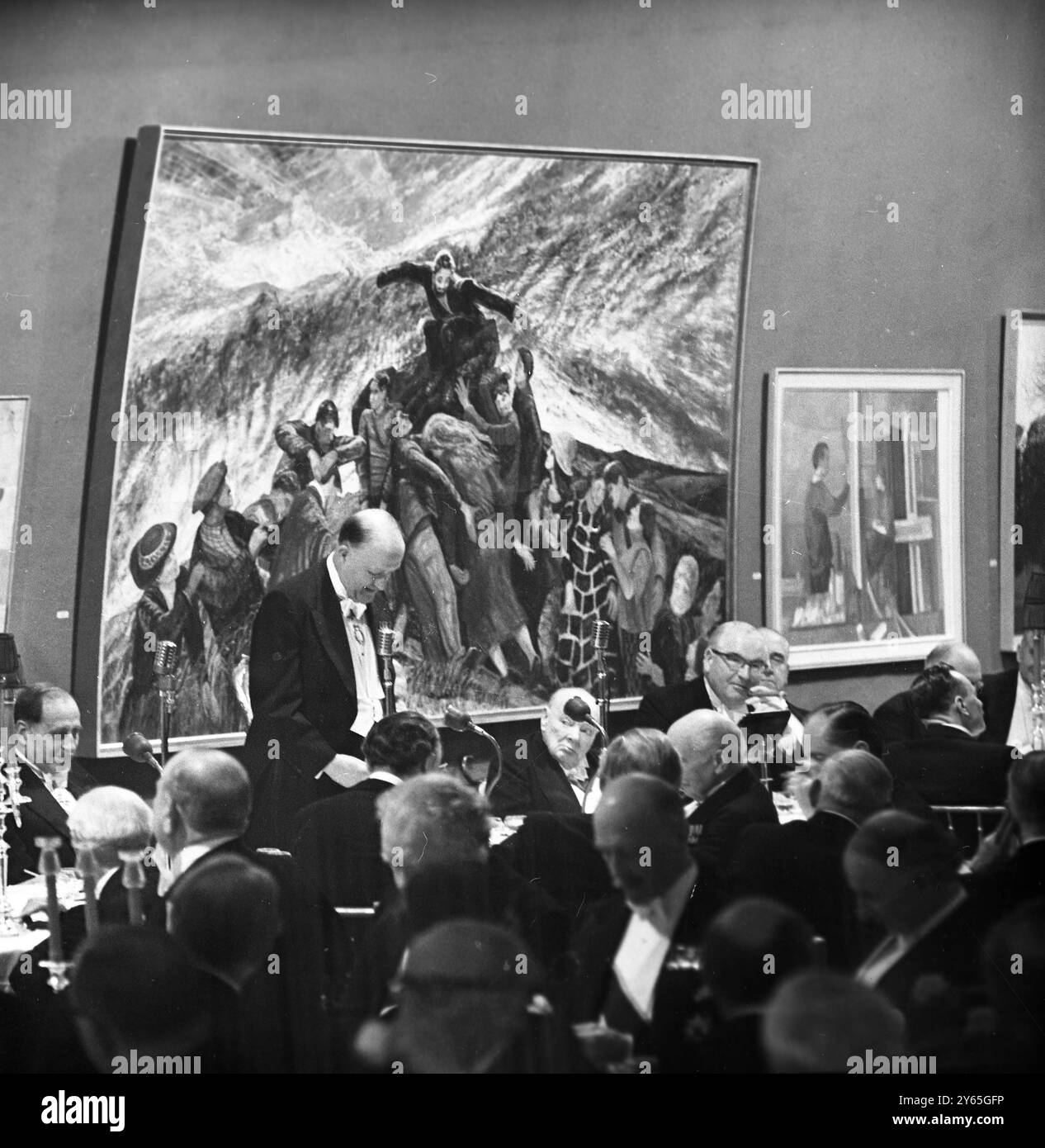 Churchill écoute debout et parlant au micro est le premier secrétaire d'État britannique , le très honorable Mr R A Butler , lors d'un dîner annuel de la Royal Academy of Arts . Assis à droite du fond et écoutant sous une fresque géante se trouve l'homme d'État aîné de Grande-Bretagne, Sir Winston Churchill, 88 ans, dont la retraite a été révélée plus tôt. 1er mai 1963 Banque D'Images