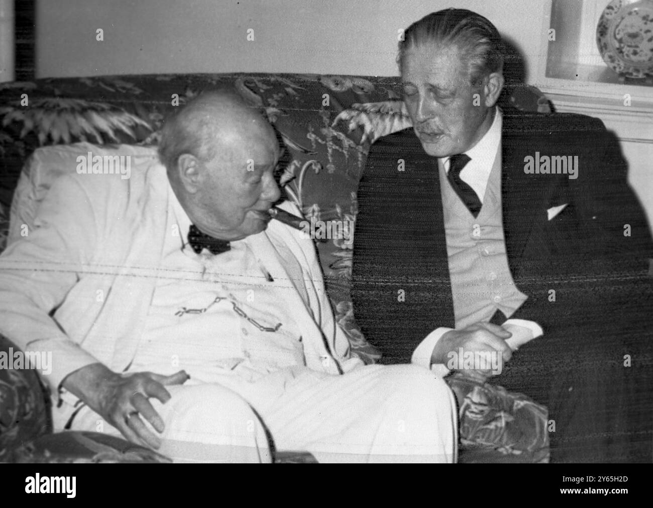 S'ils discutaient du Laos Sir Winston Churchill , vêtu d'un costume d'été blanc , et fumant son cigare habituel , ils discutaient avec le premier ministre Harold Macmillan à Government House , Trinidad , avant que Sir Winston ne poursuive sa croisière dans les Caraïbes , et que M. Macmillan s'envole pour Key West , Floride , pour avoir discuté avec le président américain Kennedy de la situation au Laos . 26 mars 1961 Banque D'Images
