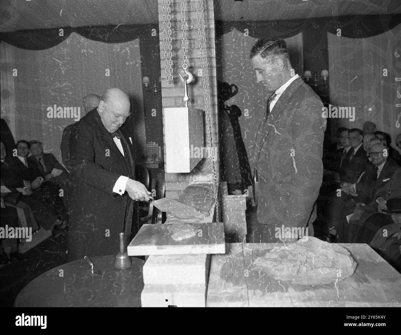Churchill pose une nouvelle pierre. Sir Winston Churchill , ancien premier ministre , se concentre alors qu'il pose la première pierre des nouveaux bureaux londoniens de Cassels the Publishers , à Red Lion Square , Londres . 23 avril 1956 Banque D'Images