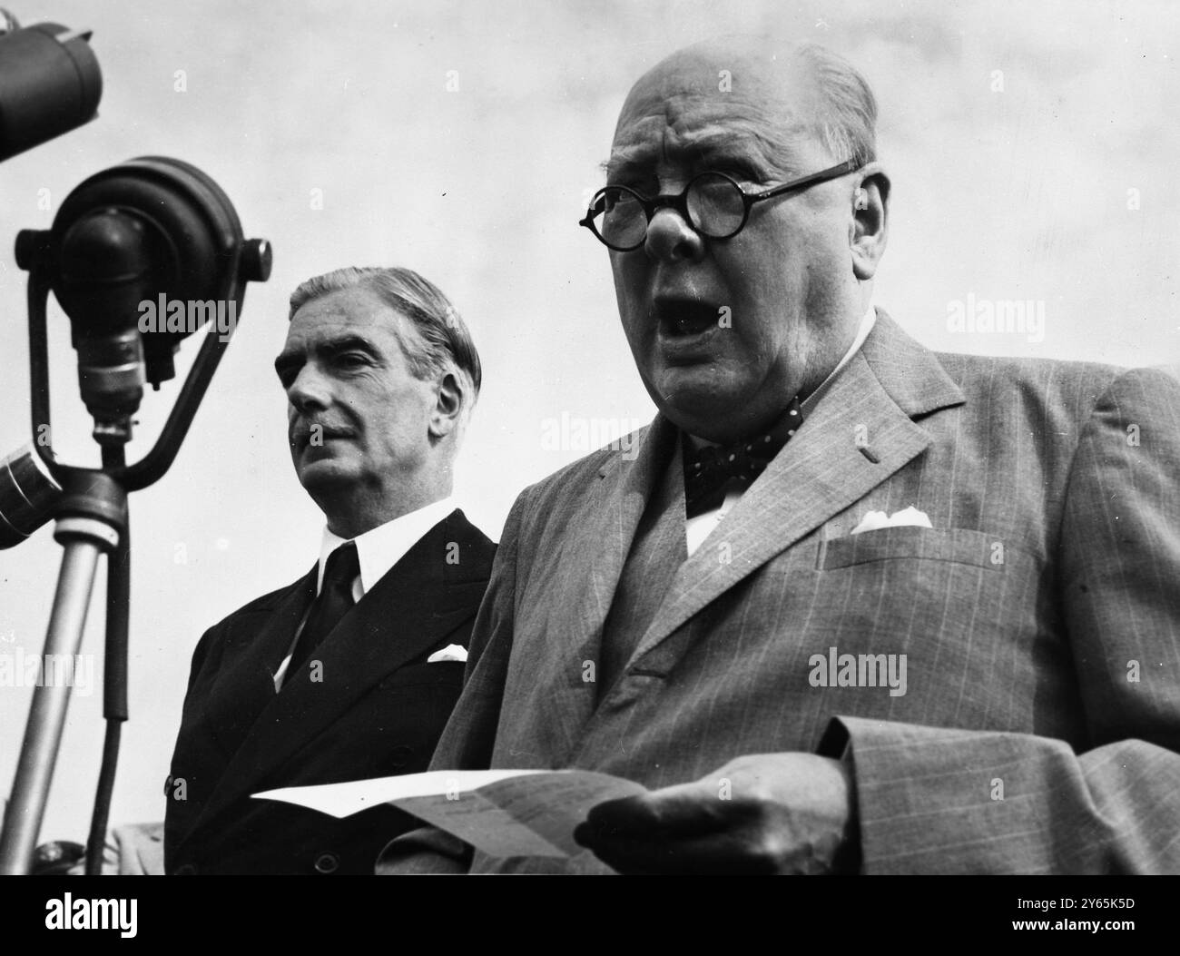 Churchill parle de son arrivée à Washington. Le premier ministre britannique, Sir Winston Churchill, a une pose impressionnante lorsqu'il dit quelques mots de salut à la foule qui l'a accueilli à l'aéroport à son arrivée pour des entretiens de haut niveau avec le président Eisenhower . Avec le premier ministre, son ministre des Affaires étrangères , M. Anthony Eden . 26 juin 1954 Banque D'Images